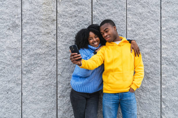 istock African young couple taking a selfie while leaning against a granite wall 2180491822