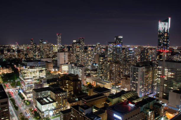 This is an impressive aerial view showcasing a vibrant city illuminated at night, with lights reflecting off the structures below, creating a stunning cityscape