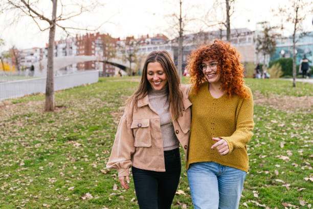 istock Two friends are walking and talking together in the park 2180493012