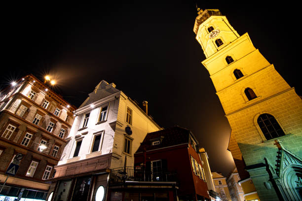 In the heart of the city at night, a beautifully illuminated clock tower stands tall, casting its glow against the darkened sky
