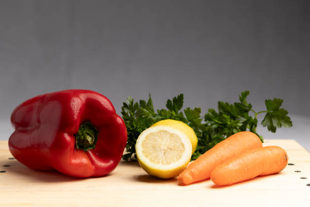 colorful vegetables, bell pepper, parsley, lemon, carrot, on light wooden board