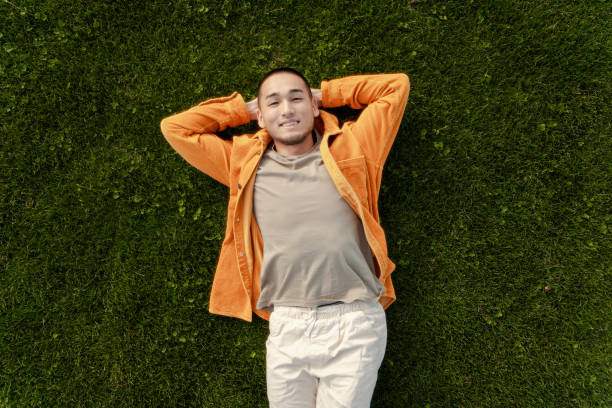 istock Young man relaxing lying down on green grass 2180501979