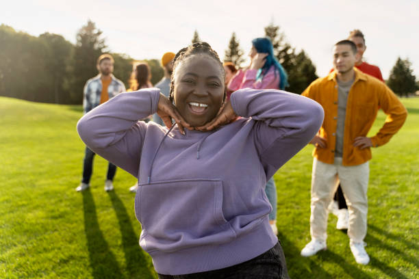 istock Young woman posing while smiling with friends in background 2180502045