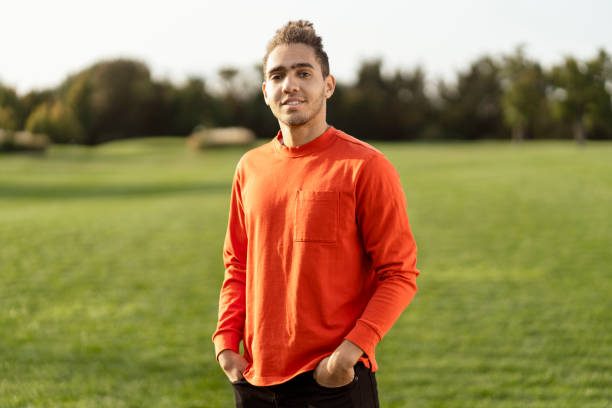 istock Young man wearing orange shirt standing in a field 2180502115