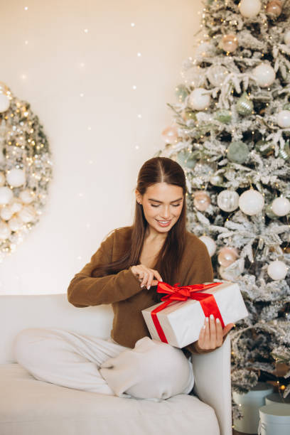 istock Woman with Gift Beside Decorative Christmas Tree at Home 2180503672