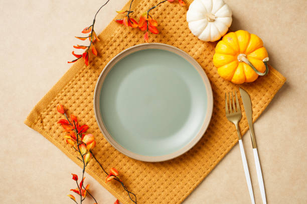 istock Elegant autumn table setting with a plate, gold cutlery, decorative pumpkins, and fall leaves. Cozy Thanksgiving dining concept. 2180507233