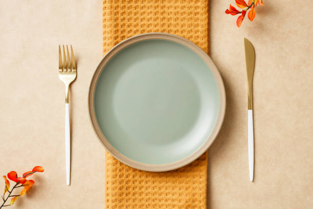 istock Elegant table setting with plate, gold cutlery, and vibrant accent flowers. Autumn, Fall, Thanksgiving dining concept. 2180507701