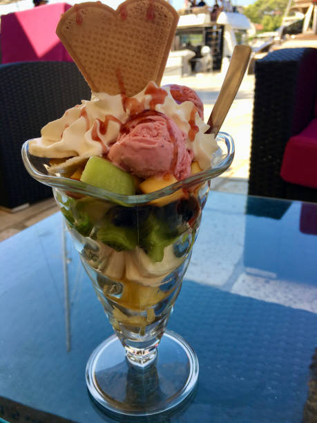 A vibrant fruit parfait topped with ice cream, adorned with a decorative wafer. This delicious treat combines fresh fruits and creamy sweetness, perfect for a refreshing snack on a warm day.