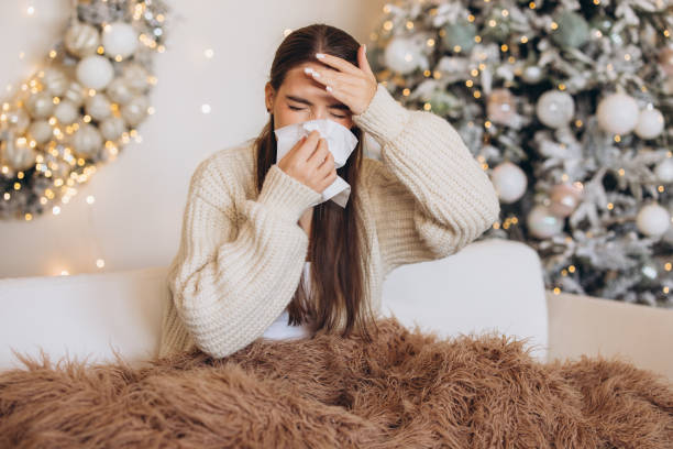 istock Woman Sneezing With Christmas Tree in Background 2180516952