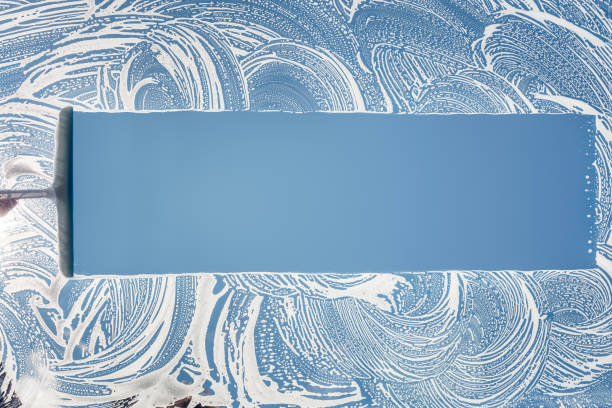 Window cleaner using a squeegee to wash and clean a window Window cleaner using a squeegee to wash and clean a window with clear blue sky washing windows stock pictures, royalty-free photos & images