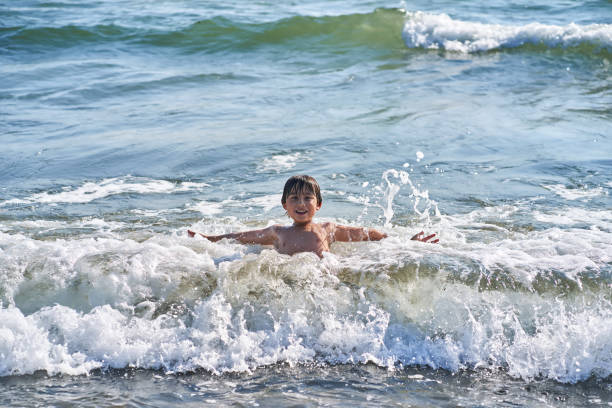 An 11 year old asian boy having fun in the sea waves. High quality photo.