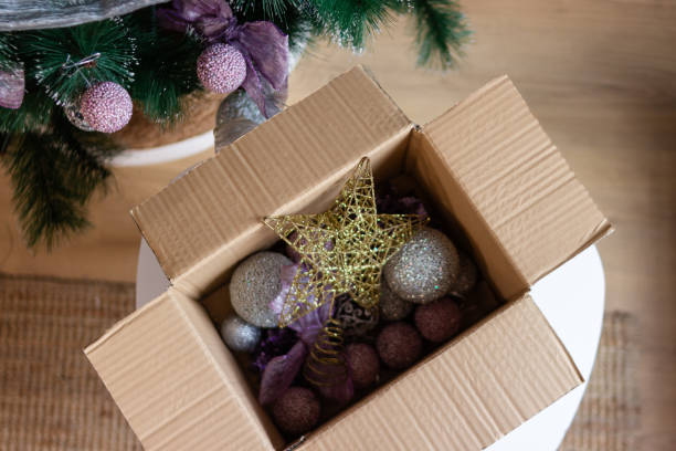 istock Christmas tree being decorated with beautiful purple ornaments from cardboard box 2180526335