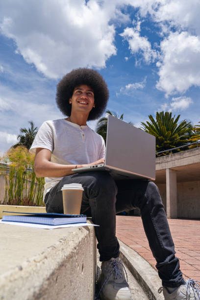 istock Young man working on his laptop on a park bench. 2180526605