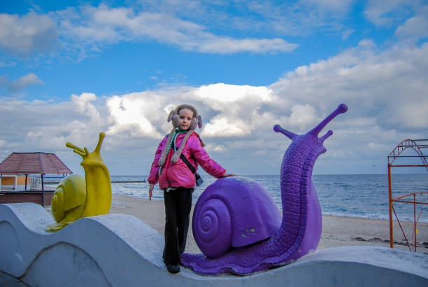 Girl and snails against the backdrop of a seascape. On the Odessa embankment there are decorative snails and a girl against the backdrop of a cloudy sky. odessa beach stock pictures, royalty-free photos & images