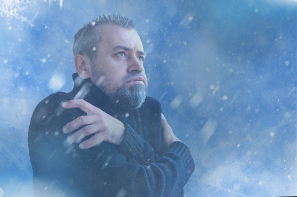 istock Frozen man shivering from cold weather on a blue snowy background. Winter cold concept 2180530538