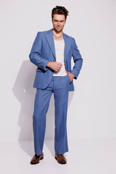 istock Trendy man in tank top and retro suit posing on grey background 2180531328