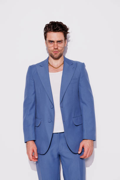 istock Stylish model in eyeglasses and vintage suit looking at camera in studio 2180531403