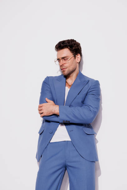 istock Stylish man in golden chain, eyeglasses and blue suit posing on grey 2180531456