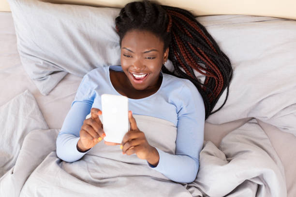 istock Hapy Girl Using Phone Holding Hands Above Lying In Bed 2180532211