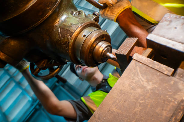 istock Focused industrial worker operating a heavy-duty drill in a workshop. The image captures precision, skill, and attention to detail, as well as the importance of safety equipment like gloves and vests. 2180540533