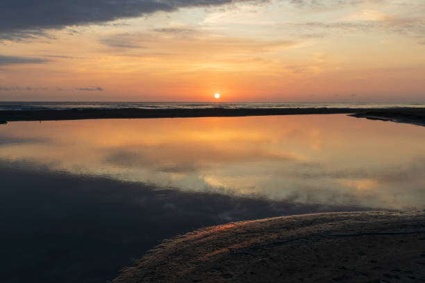 Golden sunset over a calm ocean and reflecting golden sand at sunset. Photographed in Western Australia.