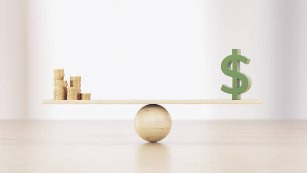 istock Coin Stacks And Green Dollar Sign On A Seesaw Before Defocused Background 2180549848