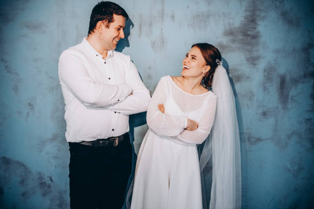 istock A smiling groom and cute bride are standing against a blue wall background 2180550182
