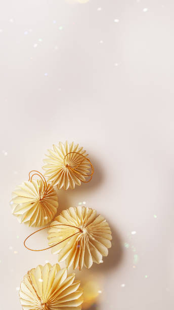 istock New Year decorative ornaments, golden Christmas flashlights shape bauble on light background, Minimal layout of paper festive decor beige balls, modern decor, top view, light effects, phone format 2180551475