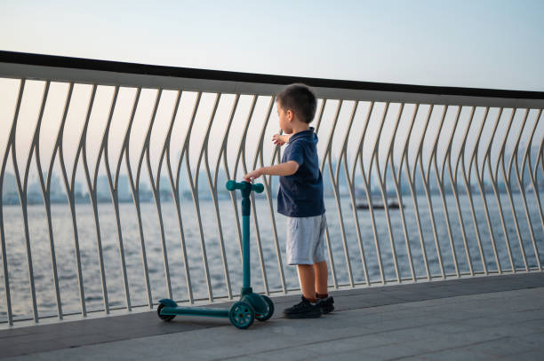 istock Happy child holding scooter near waterfront railings 2180552349