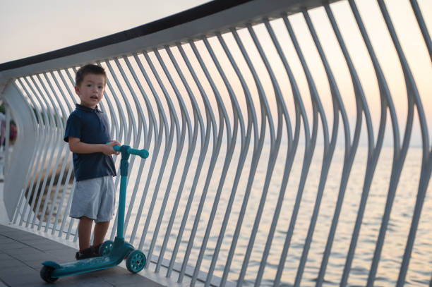 istock Happy child holding scooter near waterfront railings 2180552400