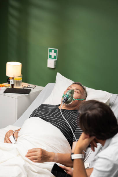 istock The elderly patient, with an oxygen mask, is in a restful sleep, supported by his son who remains by his bedside. 2180556588