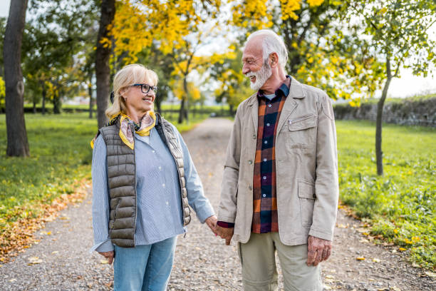istock Senior couple walking hand in hand through the park 2180558415
