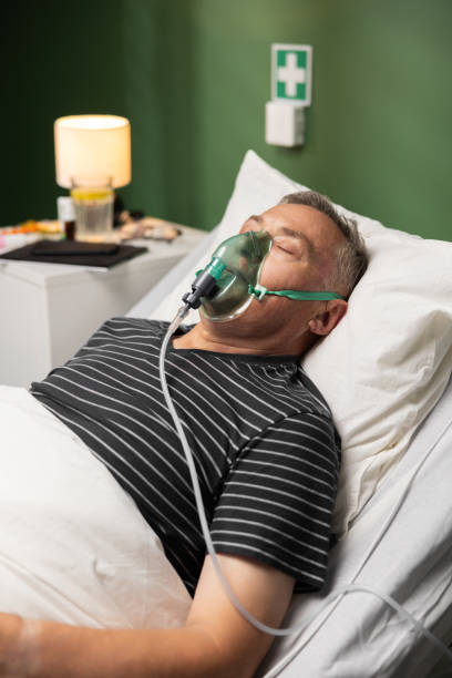 istock The elderly patient, with an oxygen mask, is in a restful sleep, supported by his son who remains by his bedside. 2180558827