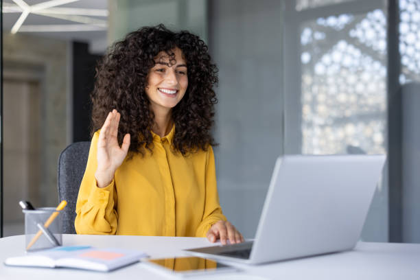 istock Hispanic businesswoman engaging in video call using laptop in modern office setting with confident and friendly demeanor 2180563221