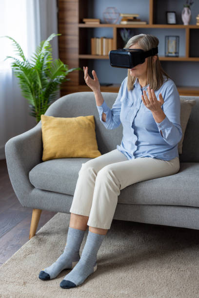 Middle-aged woman experiencing virtual reality with VR headset, seated on modern couch in apartment, exploring immersive world with excitement and wonder, casual lifestyle setting
