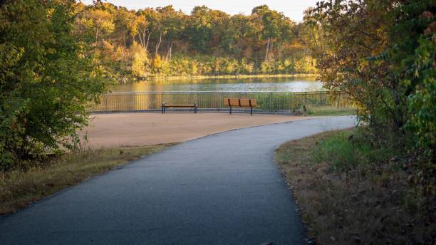 istock Serene park pathway leading to a lakeside with autumn trees. 2180567641