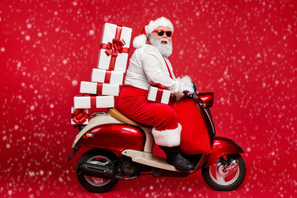 istock Profile side view of nice bearded cheerful fat funky Santa riding moped carrying pile stack fairy purchases shopping discount isolated on bright vivid shine vibrant red color background 2180583201