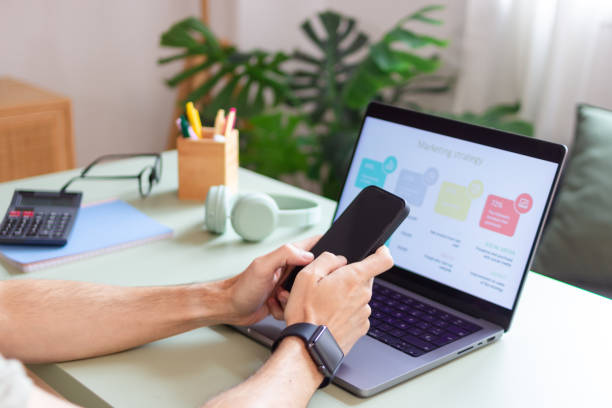 istock Marketing manager using smartphone and laptop for work from home office 2180584642