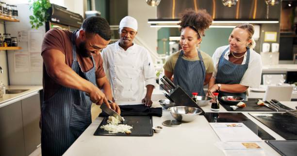 istock Cooking, class and chef teaching students in kitchen for knife skills, cutting technique and learning. Culinary course, people and mentor with lesson on food preparation and education in hospitality 2180584720