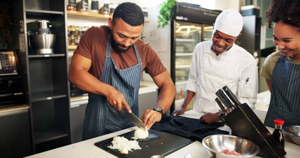 istock Cooking, course and chef teaching students in kitchen for knife skills, cutting technique and learning. Culinary class, people and mentor with lesson on food preparation and education in hospitality 2180584721