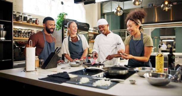 istock Cooking, class and chef in kitchen with people for meal preparation, teaching gourmet recipe or learning skills. Culinary course, laughing or mentor with lesson on food education or cuisine knowledge 2180584728