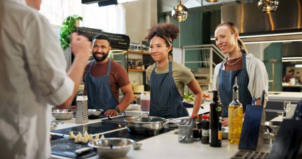 istock Learning, chef and group in kitchen, cooking and listening to instruction, mentor and teaching in hospitality. Professional, people and culinary students with smile and skills for fine dining 2180584740