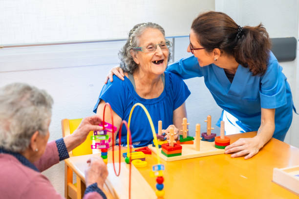 istock Senior woman and caregiver laughing while playing skill games 2180586842
