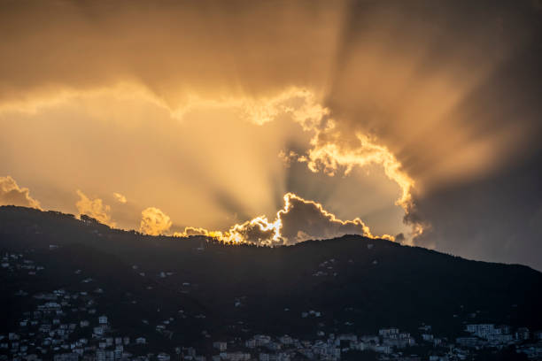 The sun is shining through the clouds, creating a beautiful and serene atmosphere. The mountains in the background add to the peacefulness of the scene