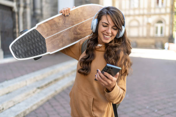 istock Beautiful smiling woman with a skateboard using cell phone 2180590367