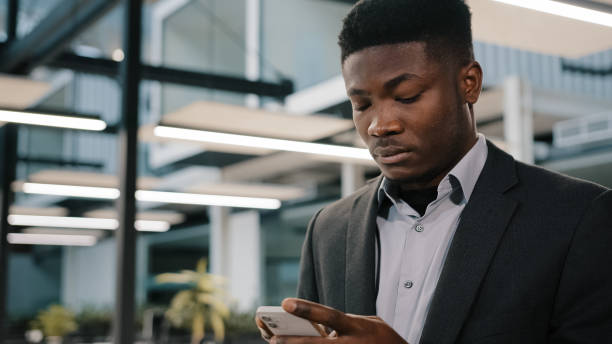 istock Thoughtful African man professional broker using mobile apps for online sales chatting with friend making order surfing internet focused analyst reading information typing message in social network 2180592170