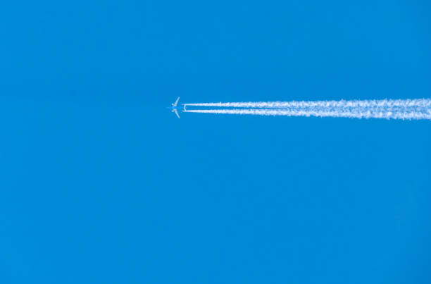 istock Airplane with Contrails Against Blue Sky 2180593560