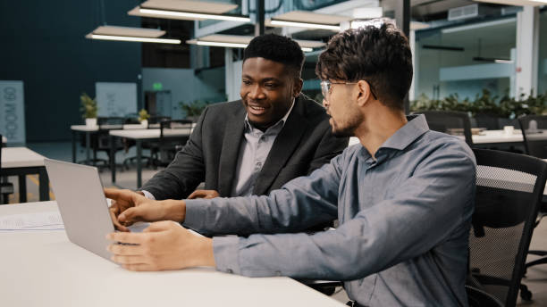 istock Arabian man financial analyst explain business strategy African entrepreneur pointing on laptop discussing startup reviewing project contract benefits negotiating having teamwork discussion in office 2180595517