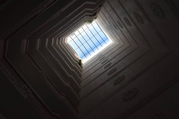 Captured from the heart of a Kayseri apartment building, this photo reveals an upward view through a geometric skywell, culminating in a bright window of blue sky. The meticulously detailed interior walls create a layered effect that draws the eye, showcasing the blend of modern design with traditional motifs. This architectural perspective embodies the city's rich heritage while inviting the viewer to ponder the vast sky beyond.