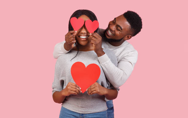istock Afro couple in love posing with valentines over pink background 2180602090